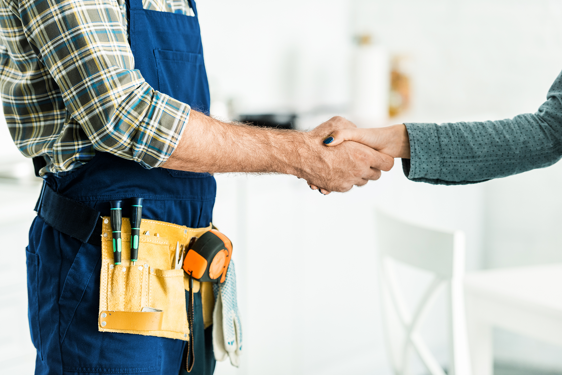 A plumber shakes hands with a homeowner after a service call
